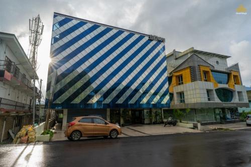 Un edificio azul y blanco con un coche aparcado delante. en Hotel The King's, en Port Blair
