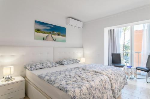 a white bedroom with a bed and a window at Casa Esmeralda 2 direkt am Strand in Benidorm