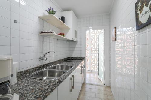 a kitchen with a stainless steel sink and a window at Casa Esmeralda 2 direkt am Strand in Benidorm