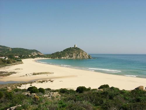 a beach with a lighthouse on a hill in the ocean at Il Gabbiano in Chia