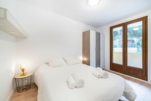 - une chambre blanche avec un grand lit blanc et 2 serviettes dans l'établissement Appartement neuf - Proche mer et centre-ville - AC, à Menton