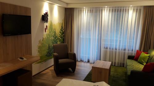a living room with a television and a couch and a chair at Hotel Ochsen in Höfen an der Enz