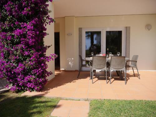 a patio with a table and chairs and purple flowers at Spacious Apartment near Porto de Mos Beach, Lagos. in Lagos