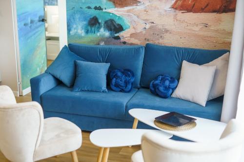 a blue couch in a living room with a table and chairs at Sunset Resort II, Nadmorska 104 in Grzybowo