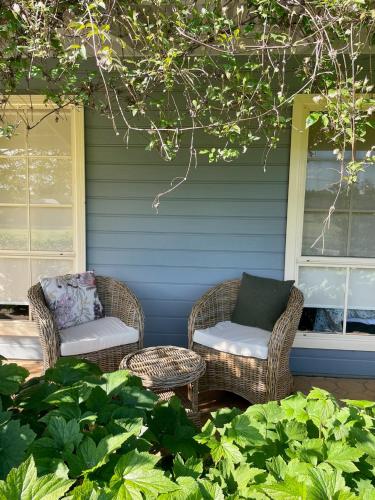 two wicker chairs and a table on a porch at Marigold Cottage, A Blue Mountains Oasis- Spacious, Views & Kangaroos in Little Hartley