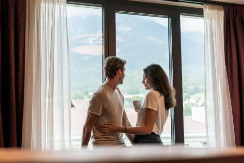 
a woman and a man standing in front of a window at Rufi's Hotel Innsbruck in Innsbruck
