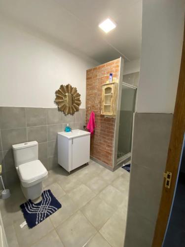 uma casa de banho com um WC e uma parede de tijolos em Twin peaks em Underberg
