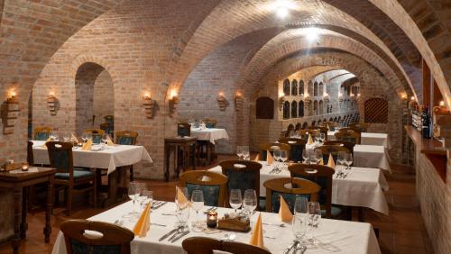 a restaurant with white tables and chairs and brick walls at Hotel Cabernet in Villánykövesd