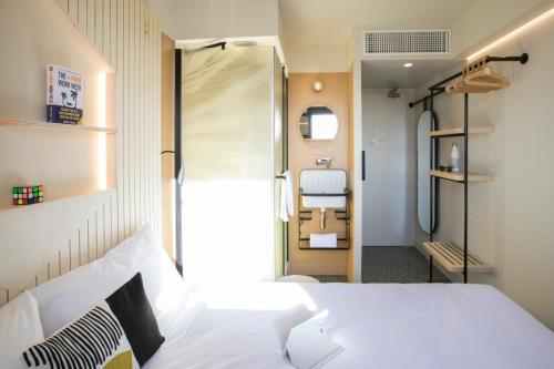 a bedroom with a white bed and a bathroom at Hôtel Life Bordeaux Gare - BG in Bordeaux