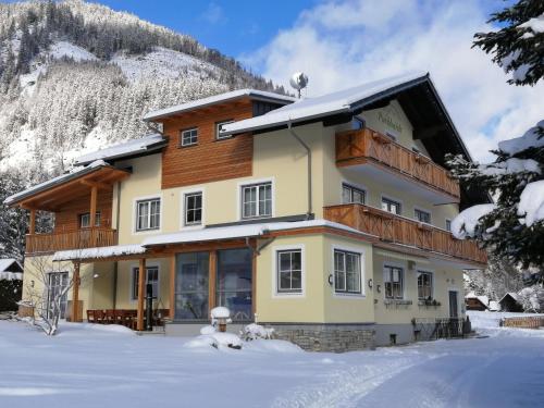 a house in the snow in front of a mountain at Familien & Wander-Pension Purkhardt in Donnersbachwald
