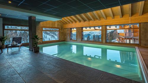 a large swimming pool with a large tub in the middle of it at Hôtel Carlina by Les Etincelles in Belle Plagne