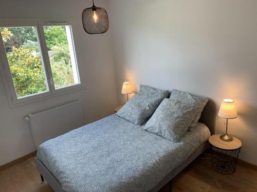 um quarto com uma cama com 2 candeeiros e uma janela em Grande maison neuve idéale pour 6 personnes em Saint-Loubès