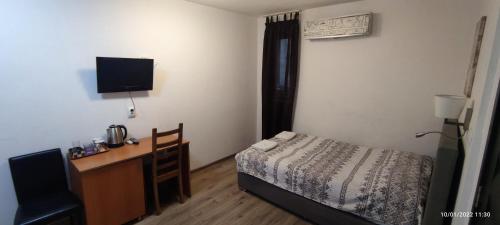 Schlafzimmer mit einem Bett und einem Schreibtisch mit einem TV in der Unterkunft Samuil Apartments in Burgas City
