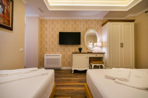 a hotel room with two beds and a television at Legacy Boutique Hotel in Korçë