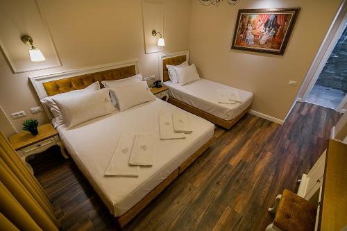 two beds in a small room with wooden floors at Legacy Boutique Hotel in Korçë