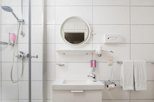 a white bathroom with a sink and a mirror at Stadt-gut-Hotel Rheinischer Hof in Essen