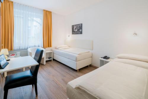 ein Hotelzimmer mit 2 Betten, einem Schreibtisch und einem Tisch in der Unterkunft Stadt-gut-Hotel Rheinischer Hof in Essen