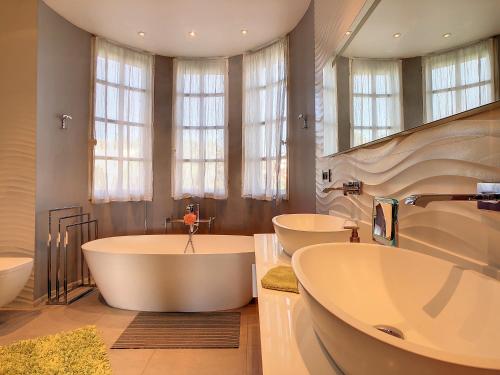 une grande salle de bain avec trois lavabos et deux baignoires dans l'établissement Un Palais au prix d'un 3 étoiles, à Cannes