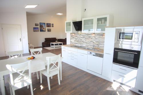 a kitchen with white cabinets and a table and chairs at Heimathafen in Tetenbüll