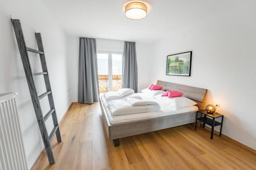 een slaapkamer met een bed met roze kussens erop bij Haus Nowak Ferienwohnungen in Millstatt