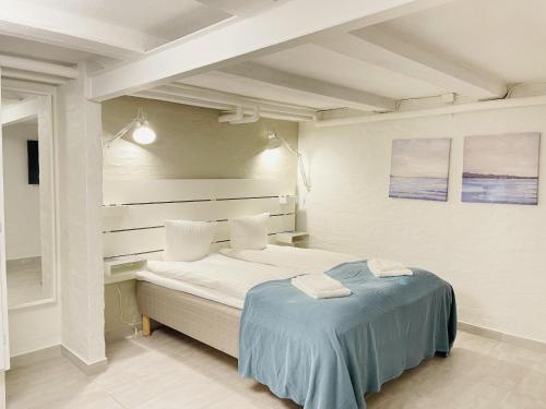 a white bedroom with a bed with blue sheets at aday - Aalborg Mansion - Charming 3 Bedroom Apartment in Aalborg