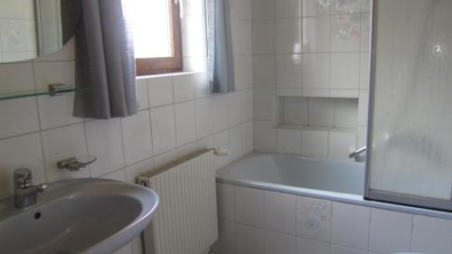 biała łazienka z umywalką i wanną w obiekcie Haus Krößbacher w mieście Fulpmes
