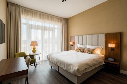 a hotel room with a bed and a window at Hotel Ter Zand - Handwritten Collection in Burgh Haamstede