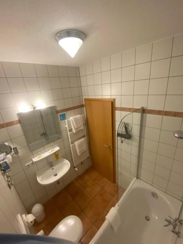 a bathroom with a tub and a sink and a shower at Hotel garni St.Georg in Sankt Wolfgang