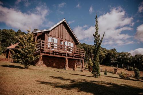uma grande casa de madeira situada no topo de um campo em Chales Pe da Serra em Gramado