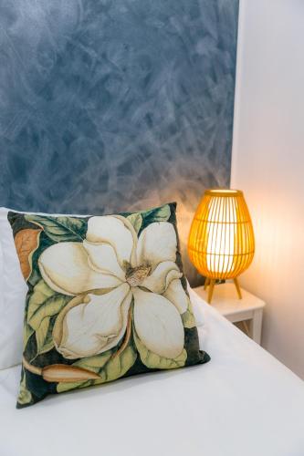 a pillow on a bed next to a lamp at Kotoisa & Tyylikäs Keskusta-asunto Neljälle! in Tampere