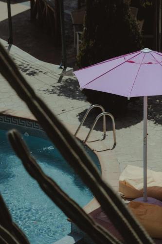 a purple umbrella sitting next to a swimming pool at Nonna's Boutique Hotel in Dhërmi
