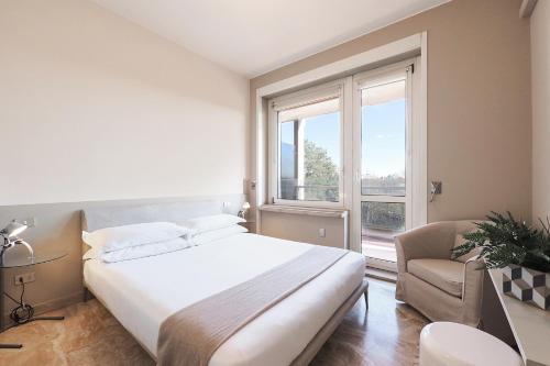 sypialnia z łóżkiem, krzesłem i oknem w obiekcie Contempora Apartments - Elvezia 8 - E52 w Mediolanie