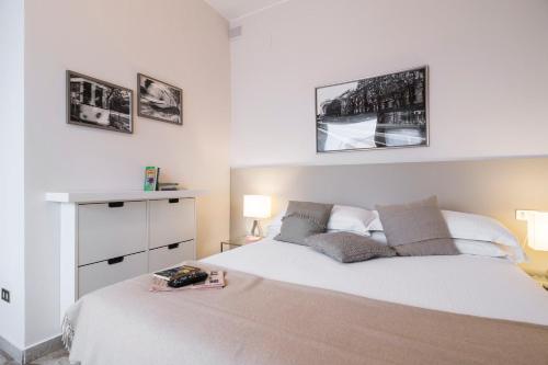 sypialnia z dużym białym łóżkiem i 2 zdjęciami w obiekcie Contempora Apartments - Elvezia 8 - E54 w Mediolanie