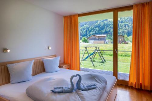 due cigni su un letto di fronte a una finestra di Apartments Susanne ad Au im Bregenzerwald