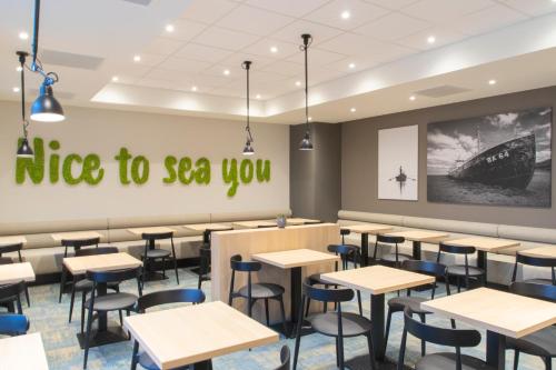 a restaurant with tables and chairs and a sign that reads rise to sea you at ibis Styles Zeebrugge in Zeebrugge