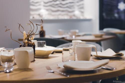 einem Holztisch mit Tellern und Utensilien darauf in der Unterkunft Logis Hôtel du Parc in Perros-Guirec