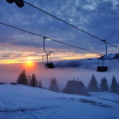 a ski lift with the sun rising above the snow at Chalet Encijan - Velika planina in Stahovica