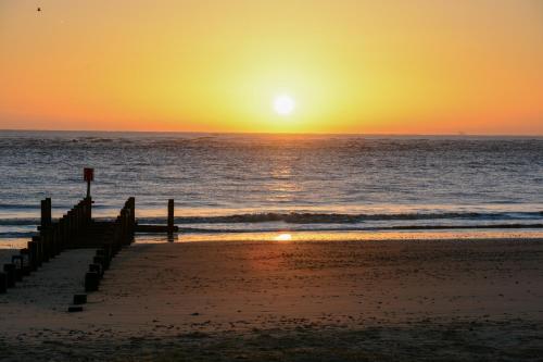 a sunset over the ocean with a pier on the beach at Sea Views Stunning 2 Bedroom Apartment # in Lowestoft