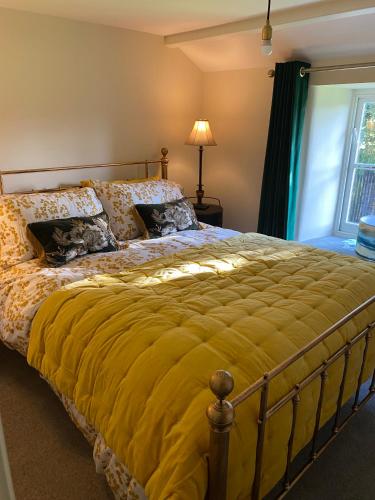 a bedroom with a large bed with a yellow blanket at Cross Haw Cottage in Sedbergh