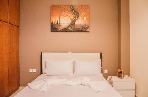 una cama con sábanas blancas y una pintura en la pared en Meli fancy Apartment, en La Canea