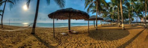 a beach with palm trees and a hammock and the ocean at Ideal Beach Resort in Mahabalipuram