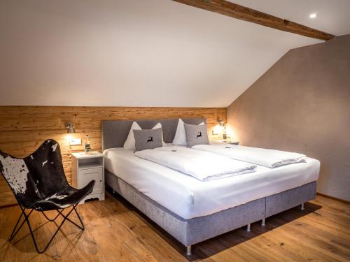 a bedroom with a large bed and a chair at Mäsers Allgäuherz in Wiggensbach