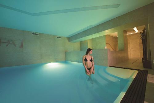a woman is standing in a swimming pool at San Severino Park Hotel & SPA, BW Signature Collection in Mercato San Severino