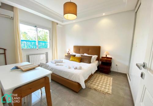 a bedroom with a bed and a table and a window at Le Safran - apt renove, spacieux et central a Marsa in Carthage