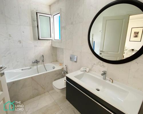 a bathroom with a tub and a sink and a mirror at Le Safran - apt renove, spacieux et central a Marsa in Carthage