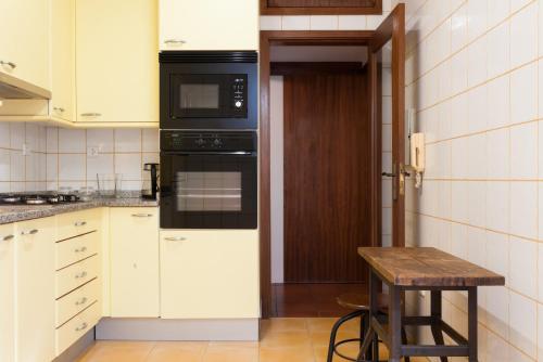 a kitchen with white cabinets and black appliances at VIVA Casa da Vila River & Sea in Porto-Family & Friends in Porto