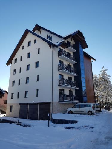 a building with a car parked in a parking lot at Gaga apartman Zlatibor in Zlatibor