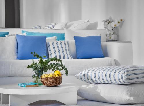 a living room with a white couch with blue pillows at Finikia Memories Hotel in Oia