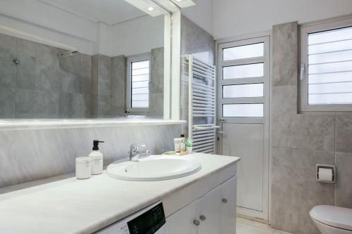 biała łazienka z umywalką i prysznicem w obiekcie Acropolis Veranda Residence w Atenach