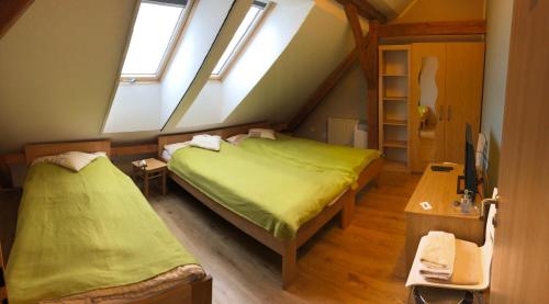 a attic bedroom with two beds and two windows at U Fousáče in Hrabětice